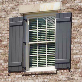 greyish blue board and batten shutters hinged on brick